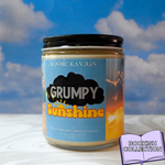 Candle jar labeled 'Grumpy Sunshine' by Kosmic Kandles with a blue sky and clouds in the background.